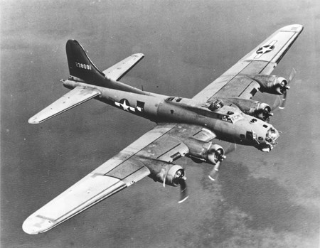 A large, four engine plane flying high over the land